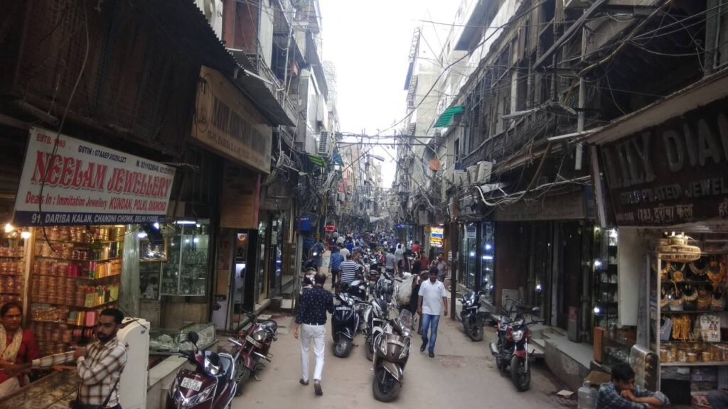 Crowdy street of Chandni Chowk with people, motor bikes and cow all together.