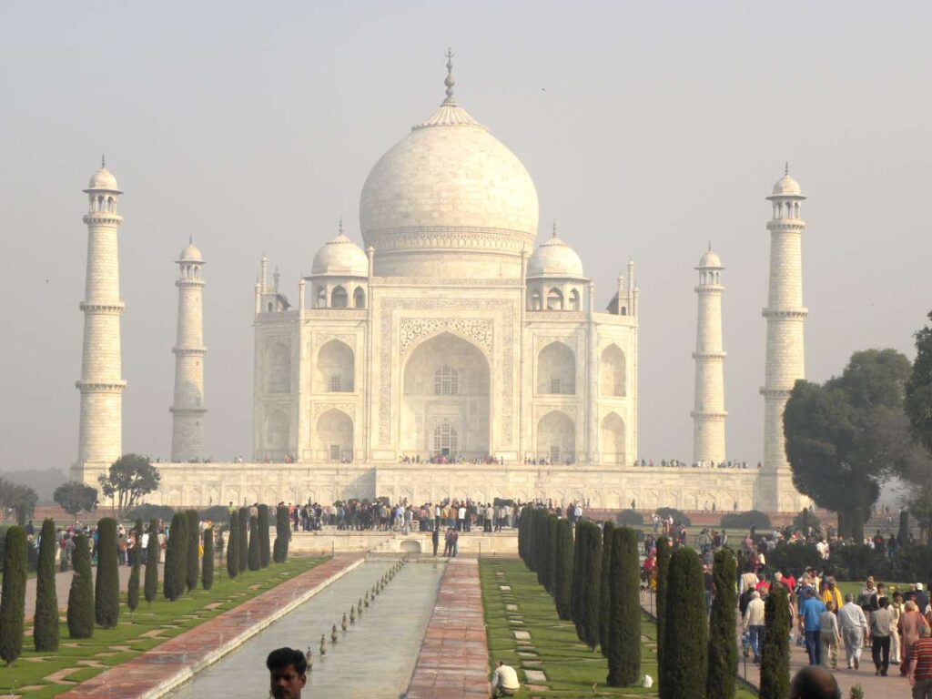 Taj Mahal with water fountain and crowd of people.